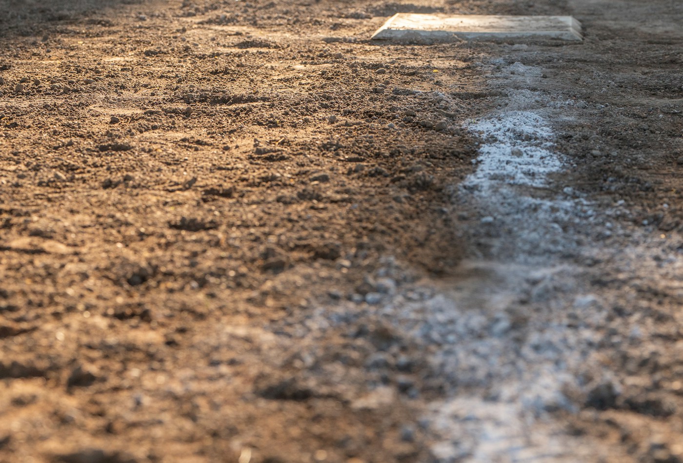 A baseball base and chalk line on an infield — illustrative stock photograph